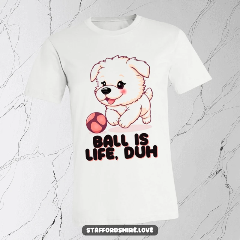 Funny, fluffy Staffordshire puppy with rosy cheeks, playfully chasing a bouncing ball on a soft, comfortable t-shirt.
