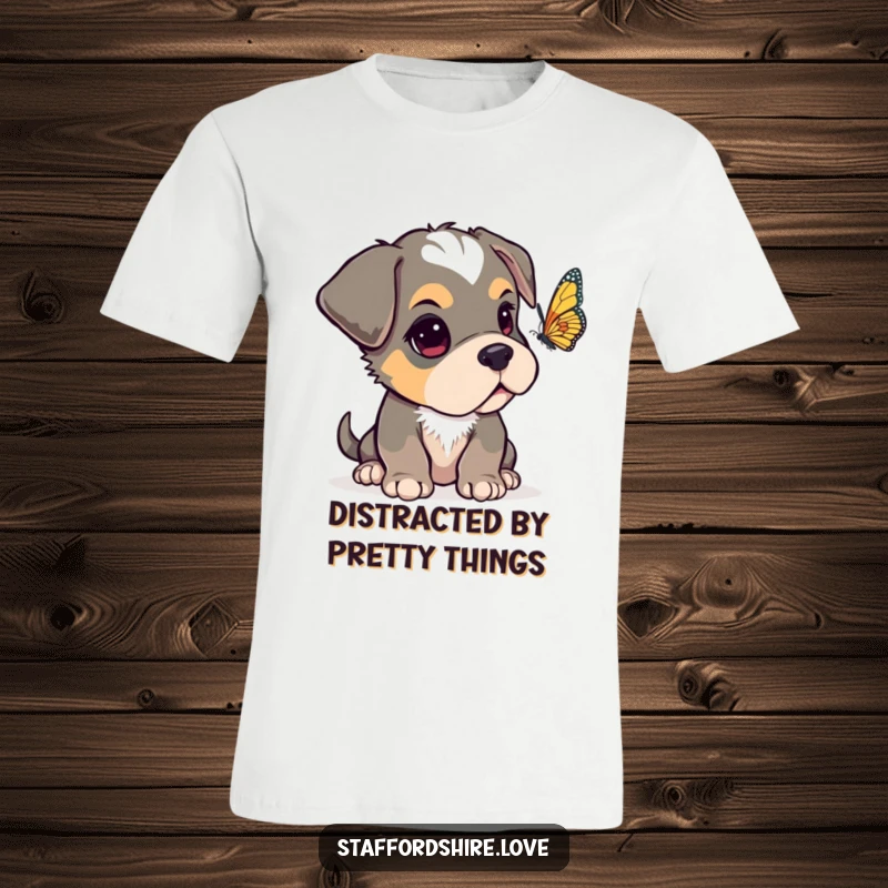 Funny Staffordshire pup with one ear flopped over, looking curiously at a fluttering butterfly on a comfortable t-shirt.