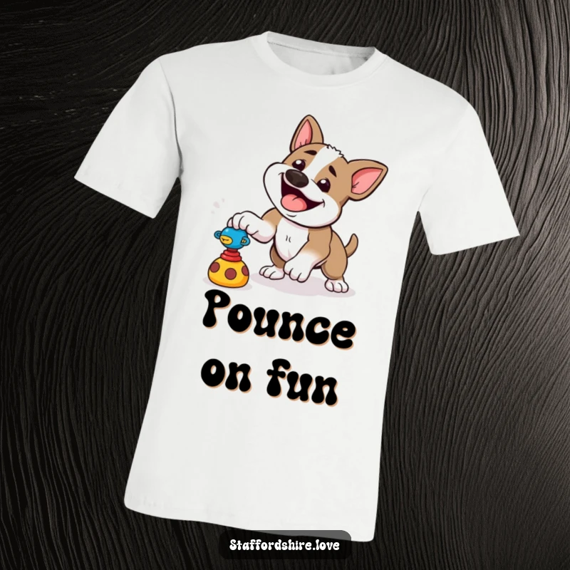 Funny t-shirt depicting a happy Staffordshire dog playfully pouncing towards a toy, radiating energy and joy.